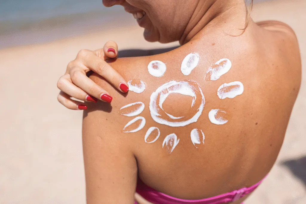 Smiling woman applying sunscreen shaped like a sun on her shoulder at the beach in Halkidiki